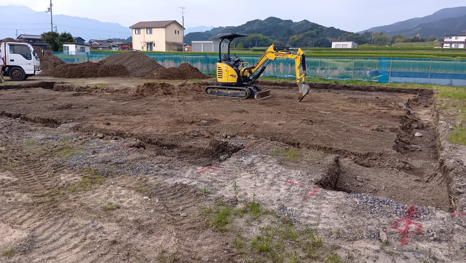 着工日の現場。重機で建物の形に地面を掘削している