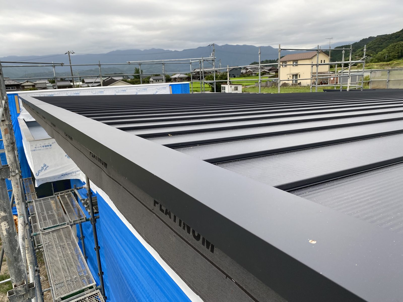 施工が完了した黒いガルバリウム鋼板の屋根。棟に換気部材が取り付けられている