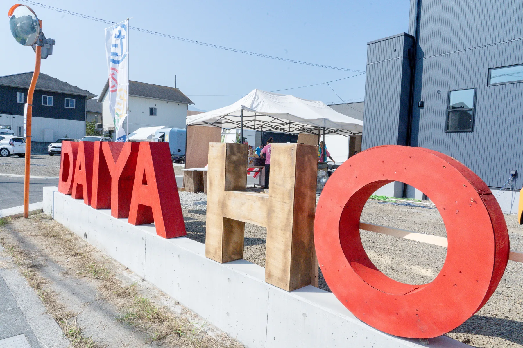 横から見た立体的な赤と木目のDAIYAHOMEロゴ