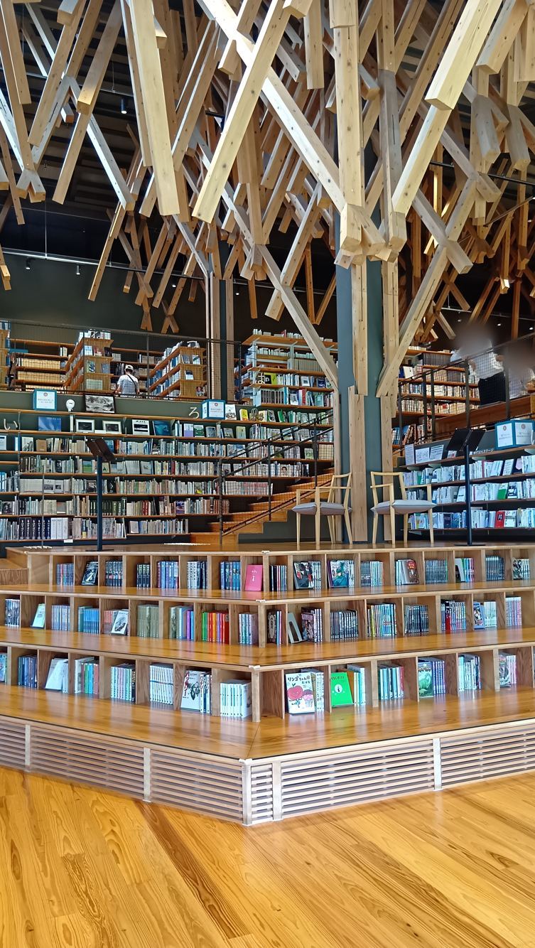 雲の上の図書館の内観。梼原町産スギの組木が天井いっぱいに広がり、階段状の床がそのまま本棚になっている