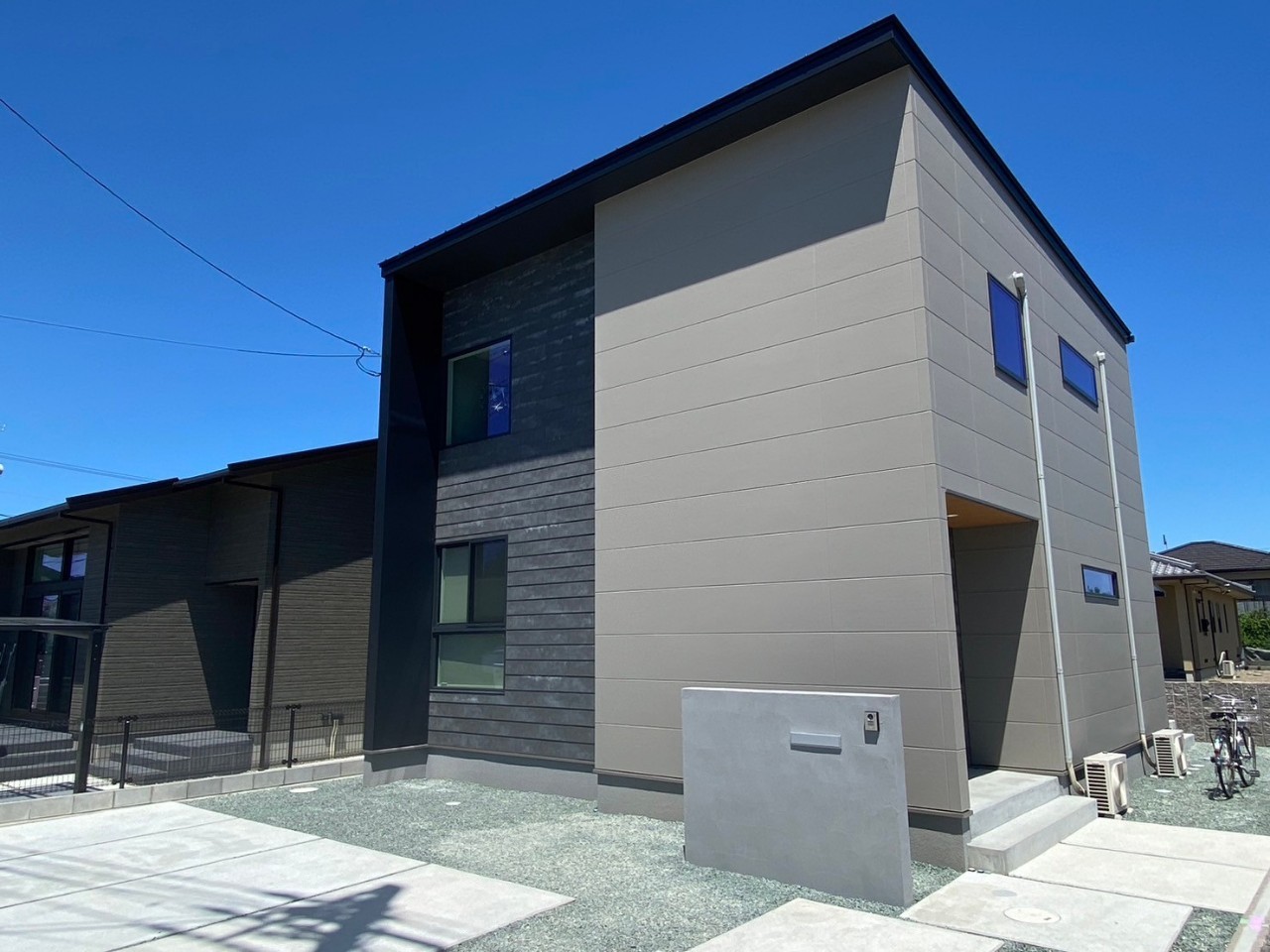 愛媛県新居浜市の2階建て注文住宅の外観。グレージュとダークトーンのツートン外壁と門柱