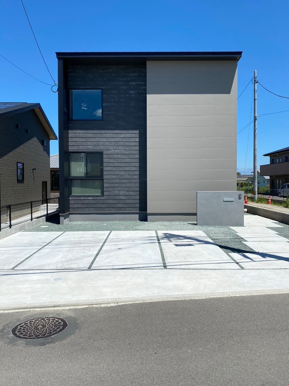 新居浜市の2階建ての外観正面。スクエアなフォルムと土間コンクリートの駐車場
