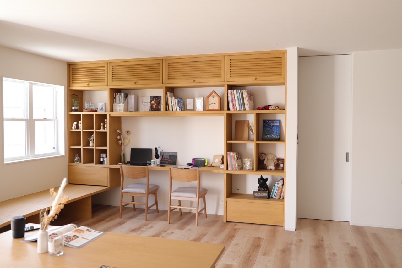 リビングの造作本棚とデスクの全景。小上がりベンチと木のテーブル