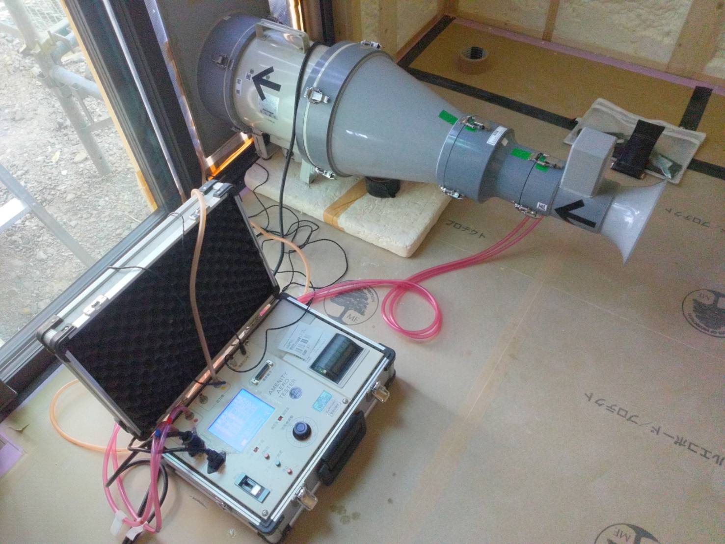 施工中の住宅で行う気密測定の様子。専用の測定器を窓に設置して家全体のすき間を計測する