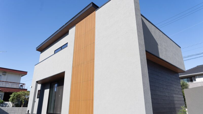 愛媛県新居浜市の2階建て注文住宅の外観。グレーの塗り壁と黒いアクセント外壁SOLID鉄黒、木製格子を組み合わせたジャパンディデザイン
