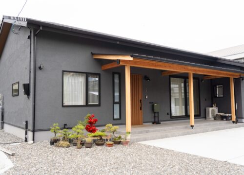 愛媛県西条市の和風平屋の外観。チャコールグレーの塗り壁と深い軒、木の柱が並ぶ注文住宅