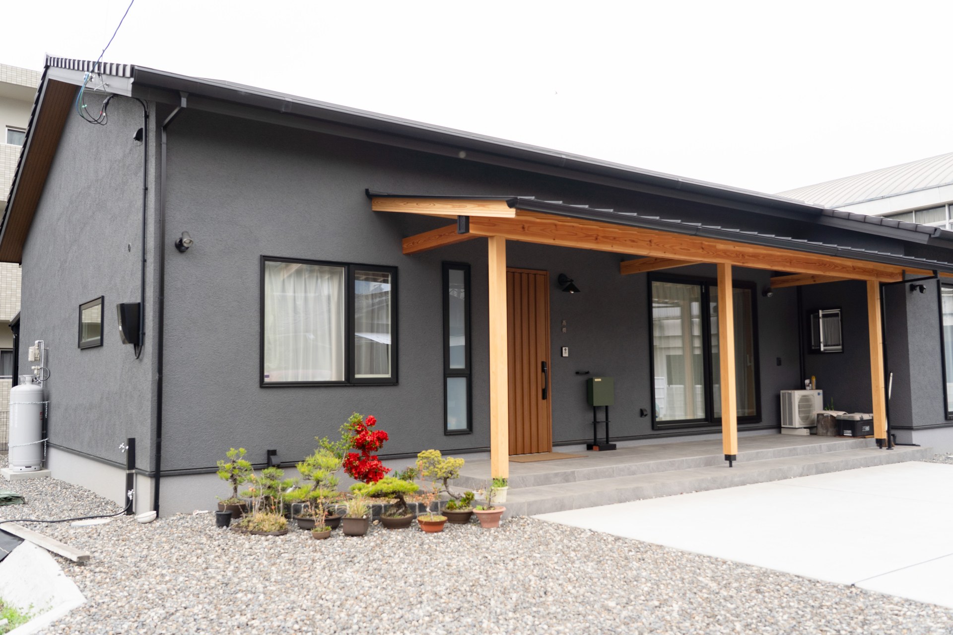 愛媛県西条市の和風平屋の外観。チャコールグレーの塗り壁と深い軒、木の柱が並ぶ注文住宅