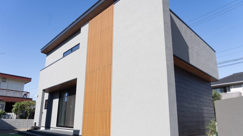 新居浜市の2階建て注文住宅の外観。グレーの塗り壁と黒いアクセント外壁SOLID鉄黒、木製格子を組み合わせたジャパンディデザイン