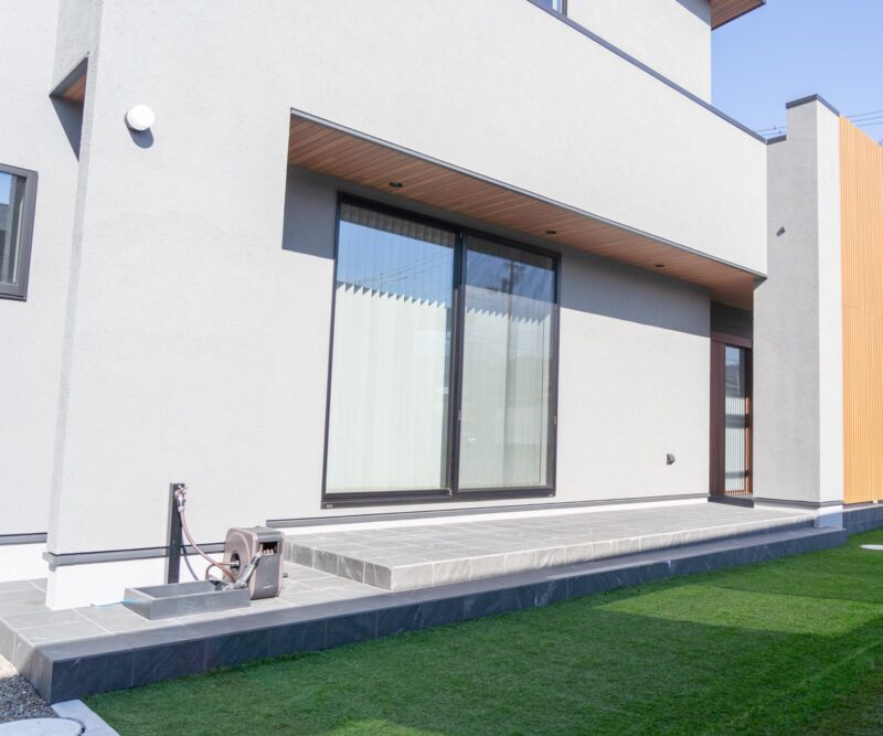 新居浜市の注文住宅のタイルデッキと人工芝の庭。リビングの大きな窓とつながり屋内外を一体に使える