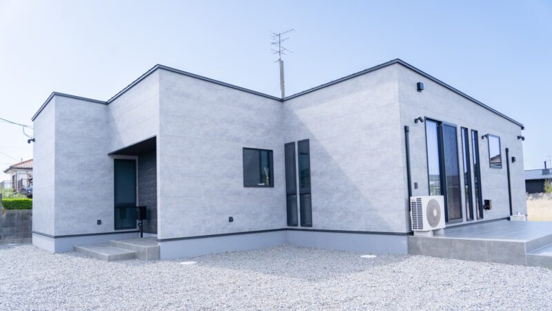 新居浜市の平屋住宅を斜めから見た外観。軒を薄く抑えた箱型のフォルムと、水平ラインを強調したグレーの外壁