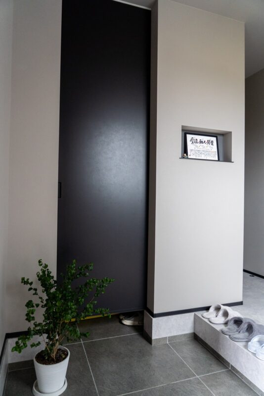 玄関の飾り棚とグリーン。黒の建具が空間を引き締めるアクセントになっている