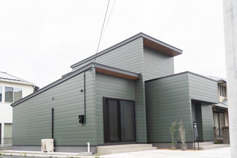 モスグリーンの金属サイディングで統一した二階建て住宅を側面から見た外観。愛媛県西条市