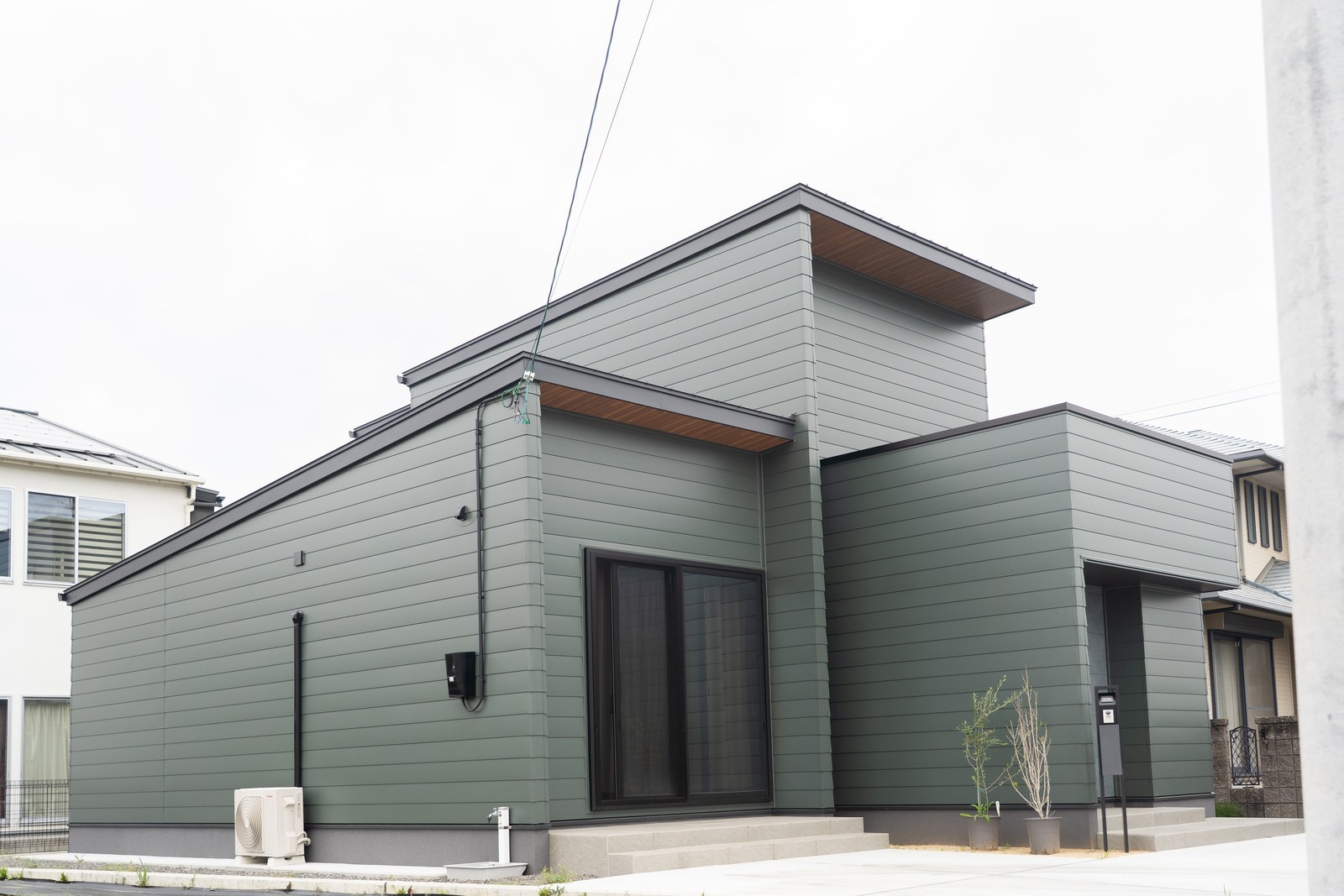 モスグリーンの金属サイディングで統一した二階建て住宅を側面から見た外観。愛媛県西条市