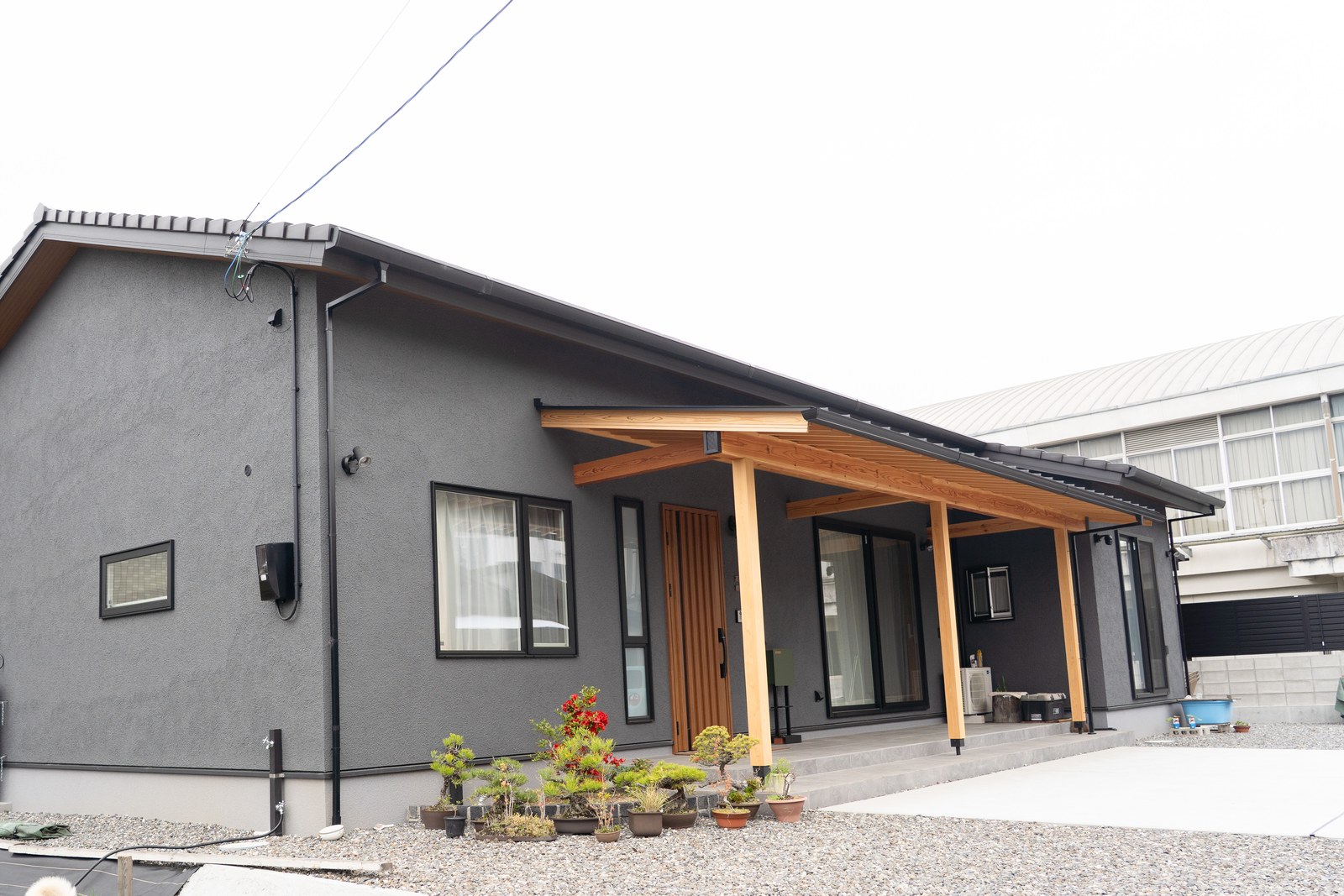 愛媛県西条市の和風平屋の外観全景。チャコールグレーの塗り壁と深い軒、木の柱が並ぶ注文住宅