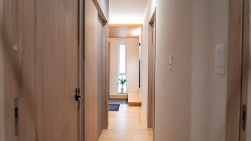 無垢フローリングの廊下。木の建具が並ぶ平屋の落ち着いた動線