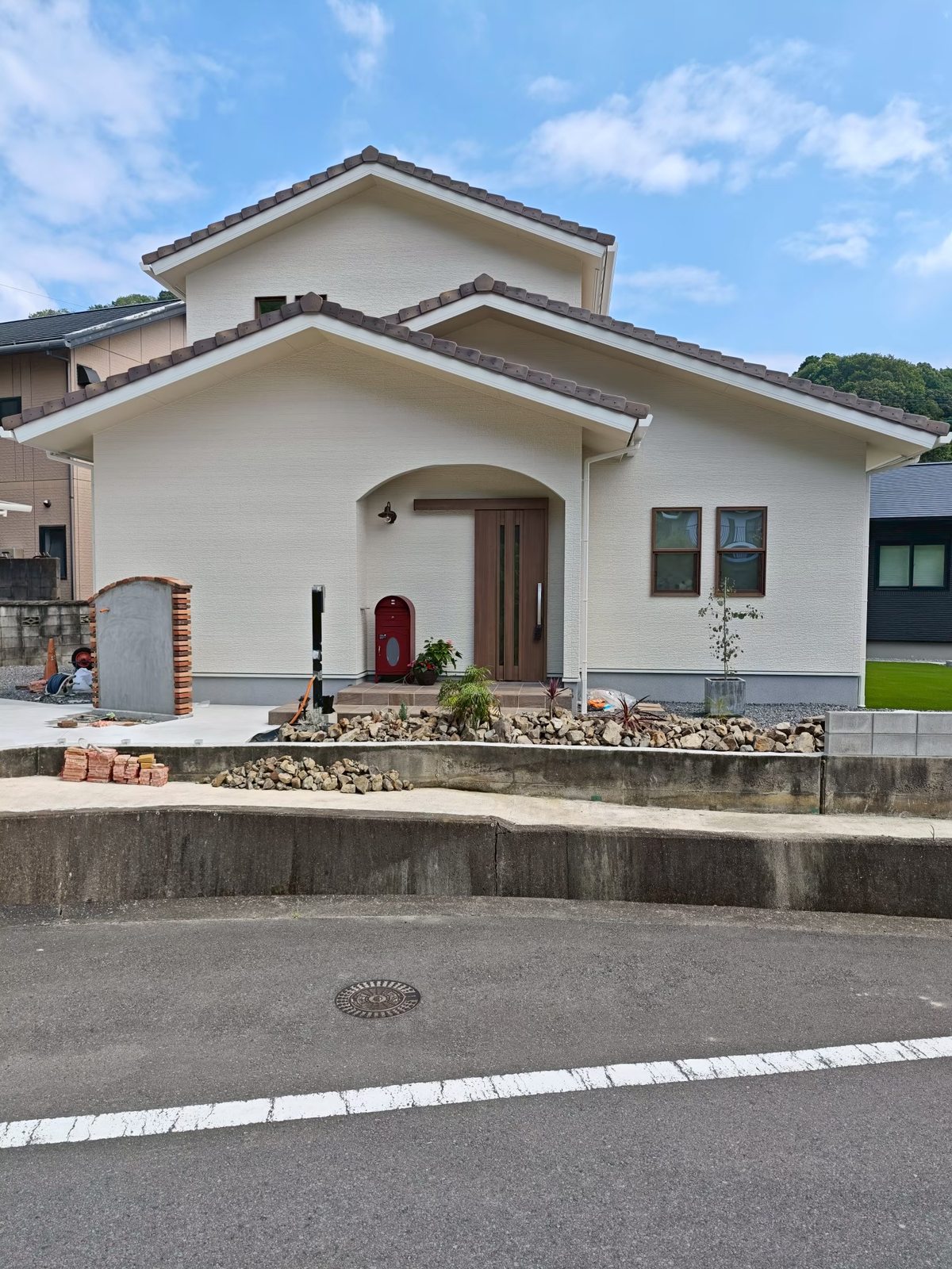 愛媛県四国中央市の南欧風2階建て住宅の外観。白い外壁にアーチの玄関ポーチと赤いポスト、瓦屋根の新築注文住宅