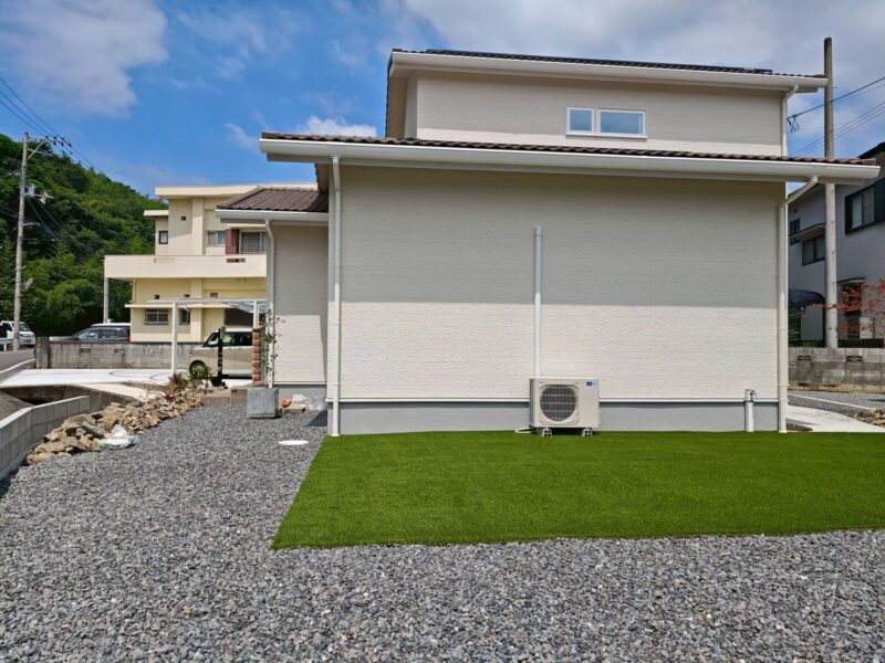 側面から見た南欧風2階建ての外観。人工芝と砕石の庭が建物を囲む