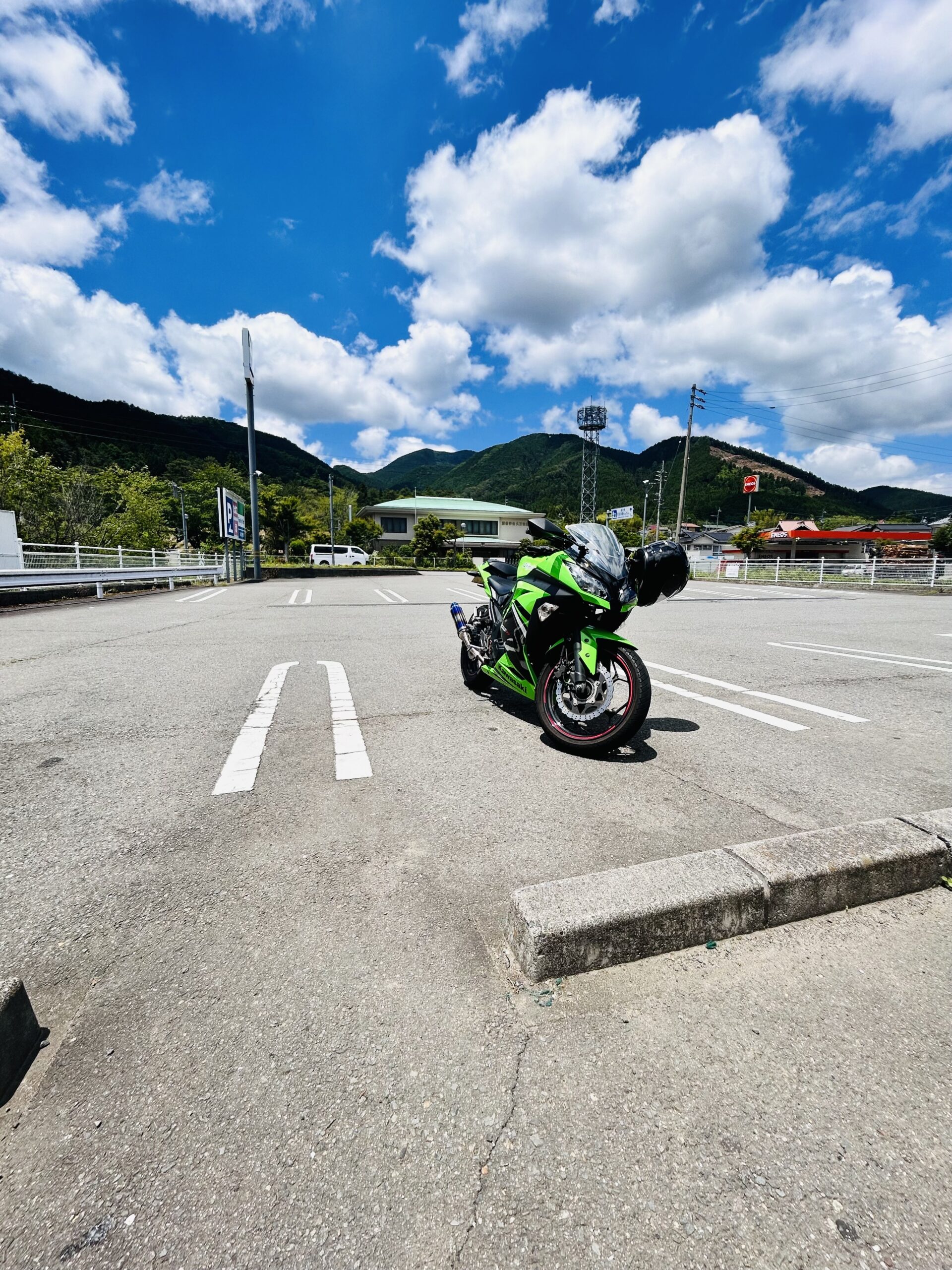 夏空と山々を背景に久万高原町で停車した緑色のバイク