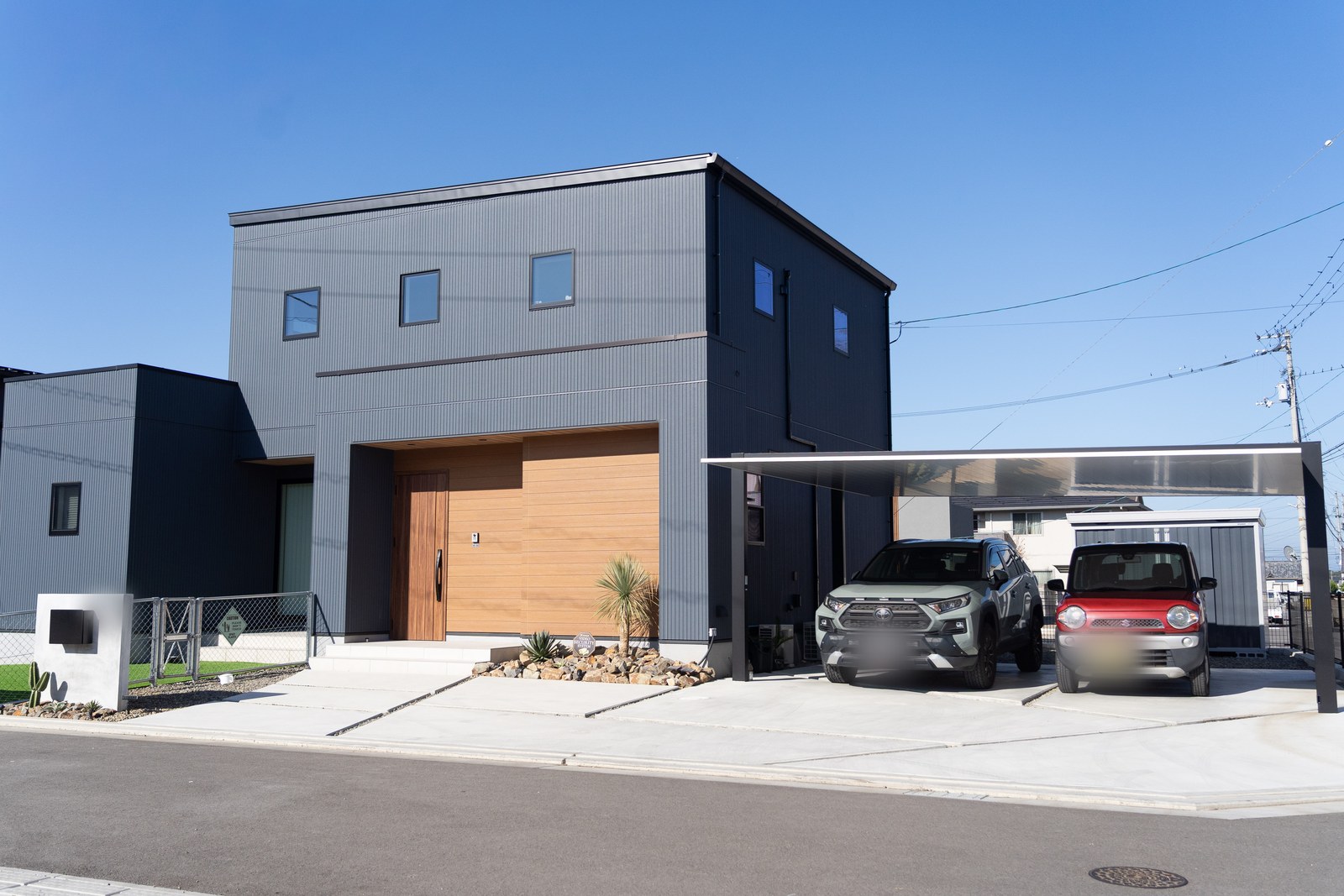 新居浜市の2階建て注文住宅の外観。箱型のシルエットにチャコールグレーの外壁、土間コンクリートの駐車場とカーポート
