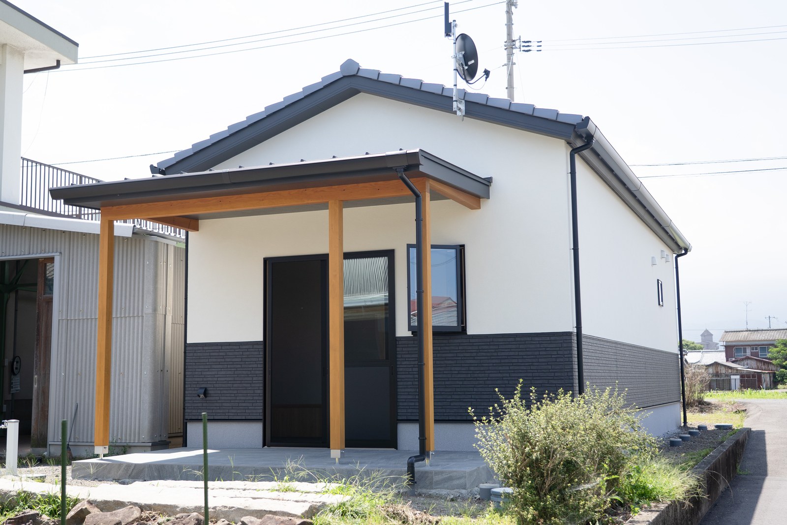 愛媛県西条市の和風平屋の外観。切妻屋根に濃色の瓦を葺き、白い塗り壁調の外壁と黒い石調サイディングの腰壁で仕上げた住まい