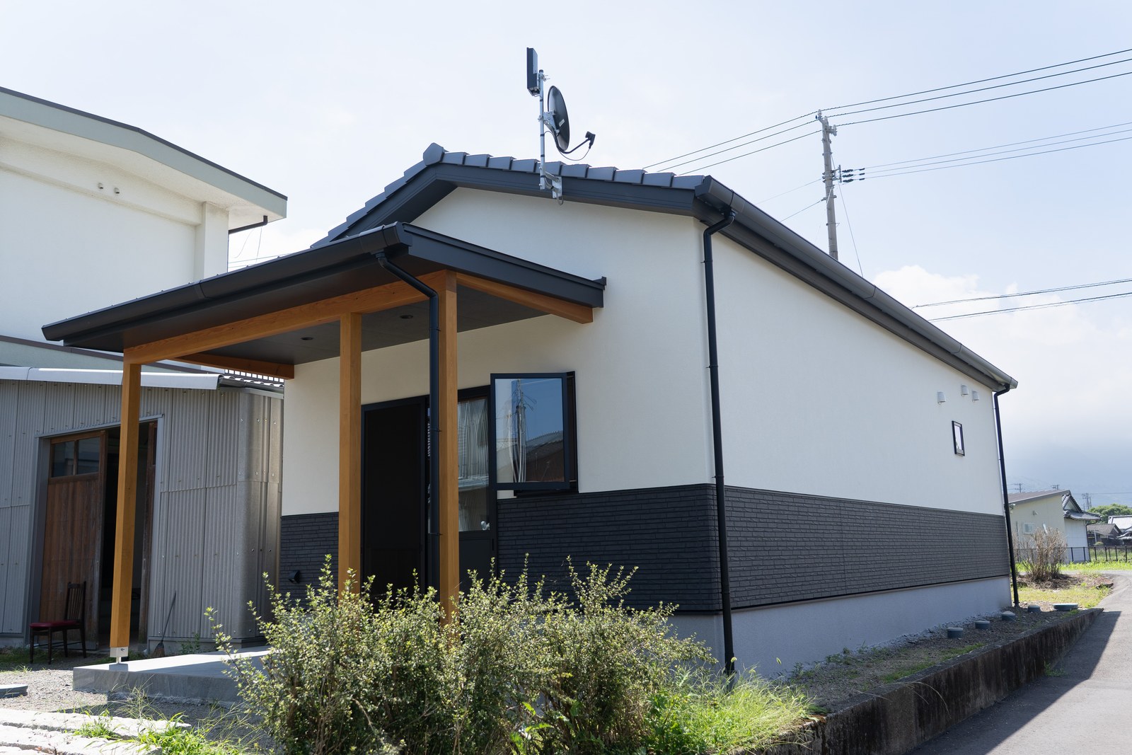 西条市の和風平屋の全景。切妻屋根の妻面の前に大きな庇屋根を張り出し、土間へ通じる深い軒下をつくっている