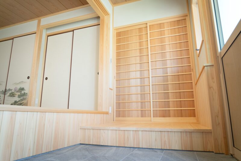 土間に立つ桧の格子戸と腰板張り。細い横桟を組んだ建具が、和の空気をつくっている