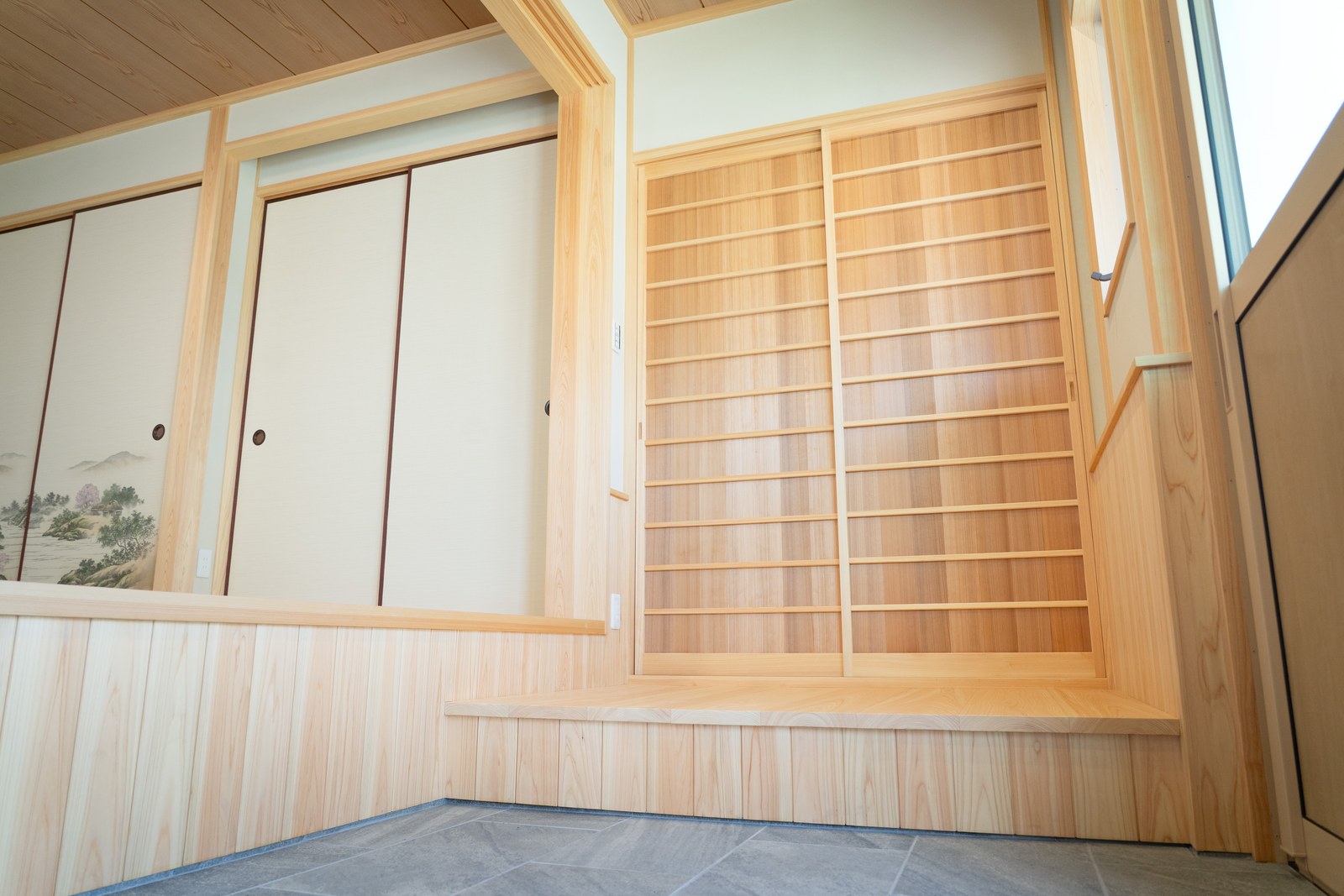 土間に立つ桧の格子戸と腰板張り。細い横桟を組んだ建具が、和の空気をつくっている