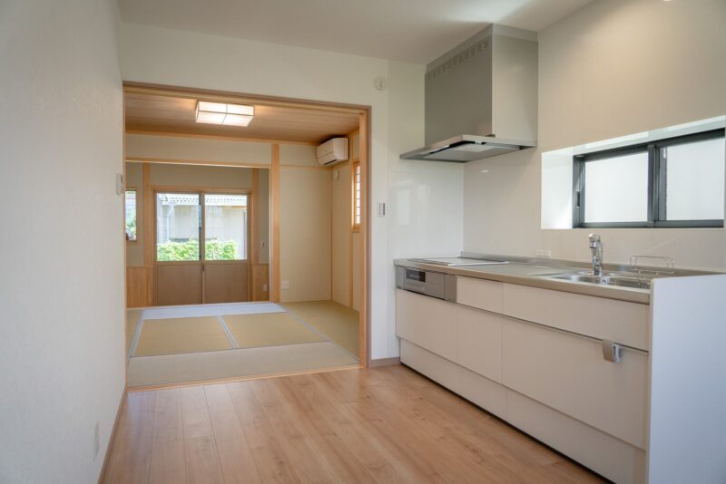 西条市の平屋のダイニングキッチンから和室を見たところ。建具を入れず、天井まで抜けた大きな開口でつないでいる