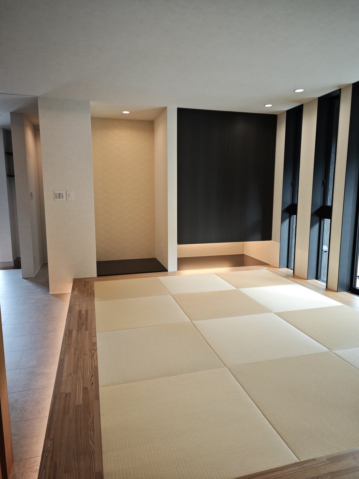 足元に間接照明を仕込んだ市松模様の畳の小上がりと、麻の葉柄のクロスを貼った床の間風のニッチ、浮かせた黒い木目の収納